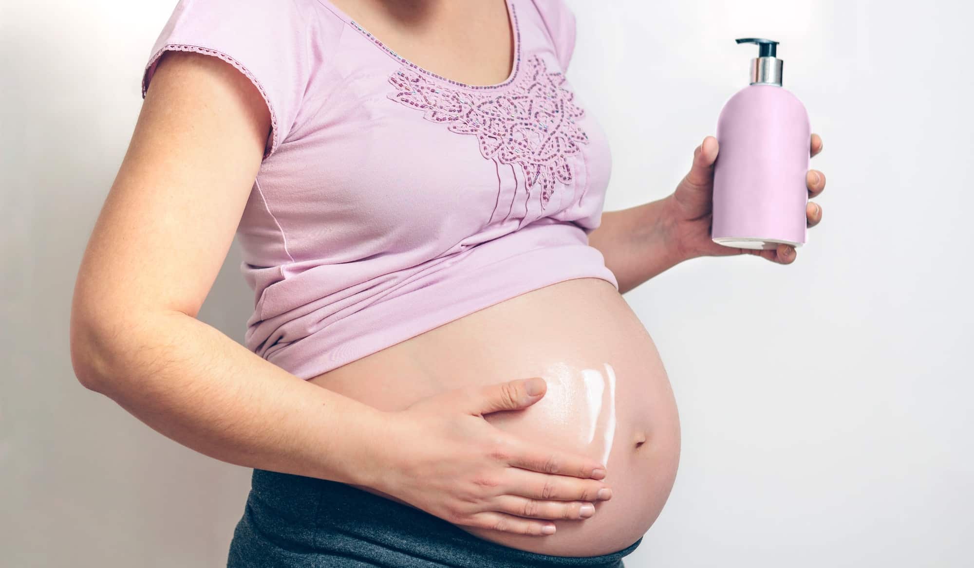 Pregnant applying anti-stretch mark cream