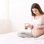 Pregnant woman applying stretch mark cream to belly