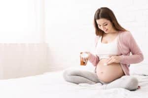 Pregnant woman applying stretch mark cream to belly