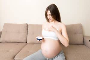 pregnant woman applying stretch mark cream to belly. pregnancy, people