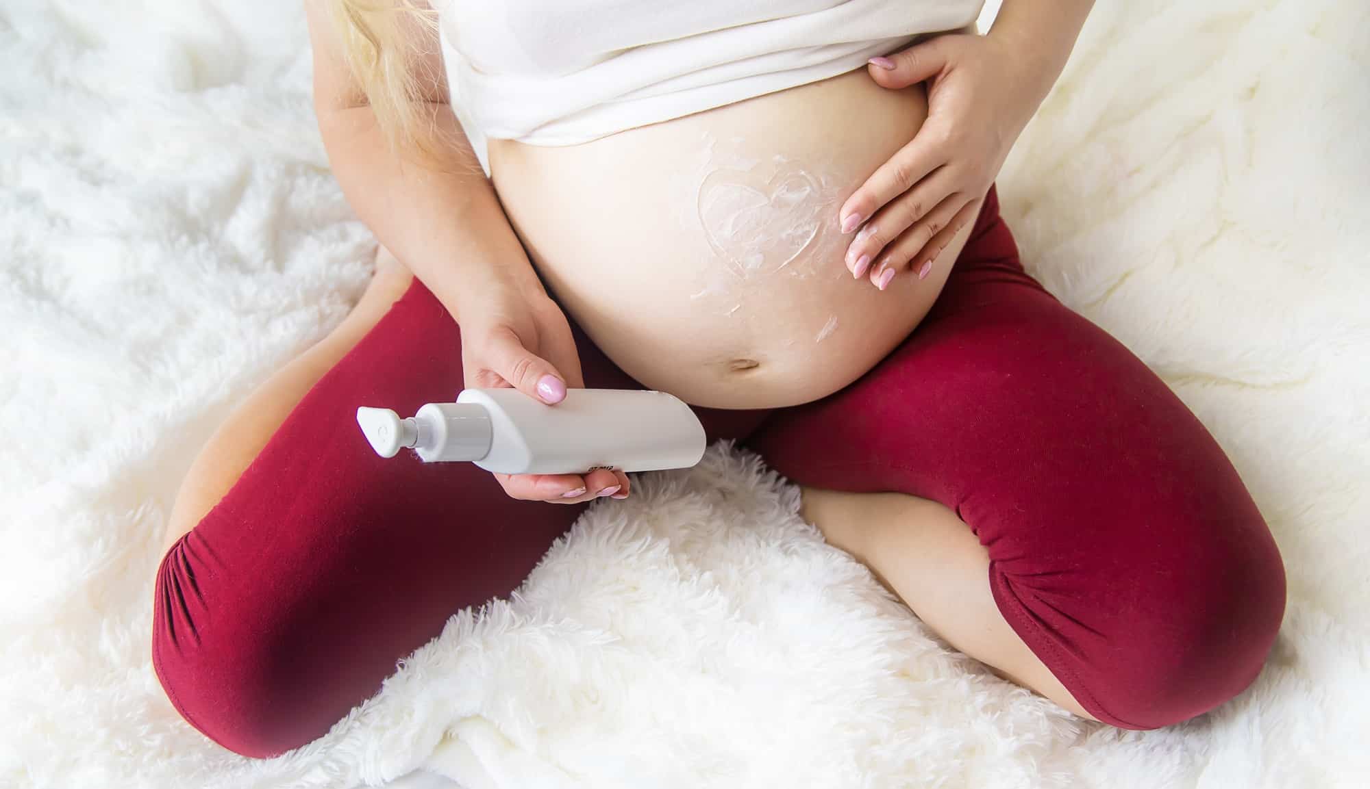 Pregnant woman smears cream from stretch marks. Selective Focus.