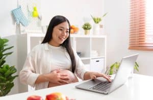 Pregnant woman using laptop at home.