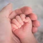 person holding baby's hand in close up photography